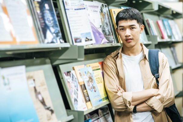 men carrying a backpack and searching for books in the library.