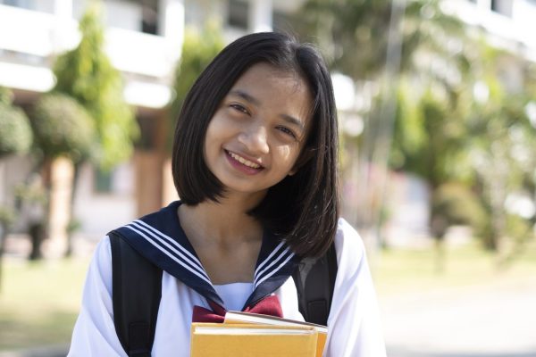 Beautiful Asian student hold book at school.